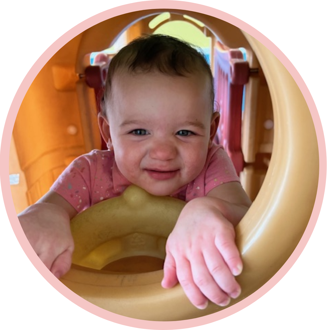 A baby is smiling in the play area.